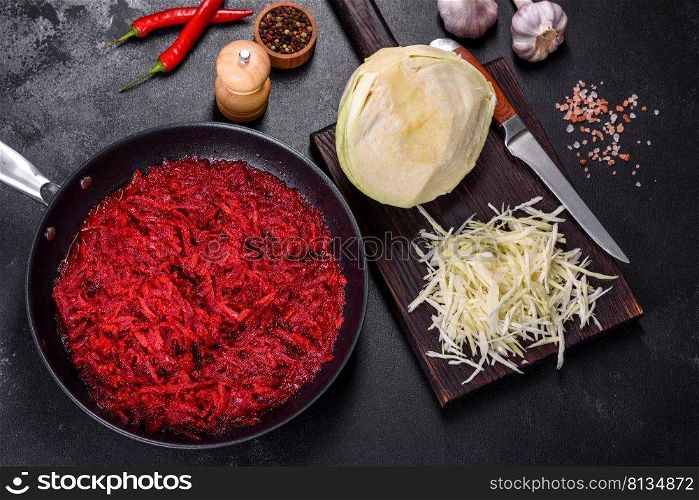 Chopped beetroot in a pan as well as spices and herbs on a wooden cutting board as ingredients in the preparation of traditional Ukrainian borscht. Chopped beetroot in a pan as well as spices and herbs on a wooden cutting board