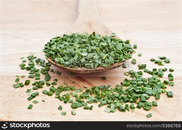 Chopped chives on wooden serving spoon with shallow depth of field