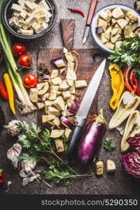 Chopped eggplant on wooden cutting board with knife and various vegetarian cooking ingredients for healthy eating , top view. Balkan cuisine concept