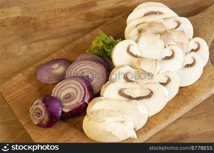 Chopped fresh raw onion and mushroom on a wooden board