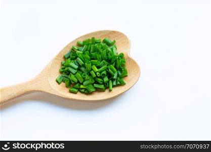 Chopped green onions and heart shape spoon on white background