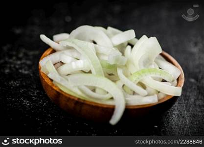 Chopped onions in a wooden plate. On a black background. High quality photo. Chopped onions in a wooden plate.