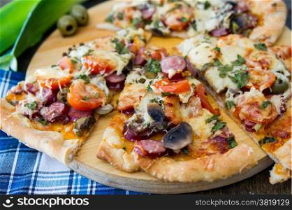 chopped pieces of pizza with mushrooms, olives, salami and pepper