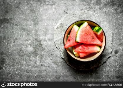 Chopped pieces of watermelon in a bowl. On the stone table.. Chopped pieces of watermelon in a bowl.