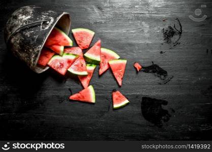 Chopped pieces of watermelon in an old pot. On the black wooden table.. Chopped pieces of watermelon in an old pot.