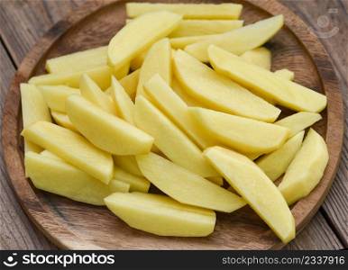 chopped potatoes for cooked food on wooden bcakground, fresh raw potato wedges