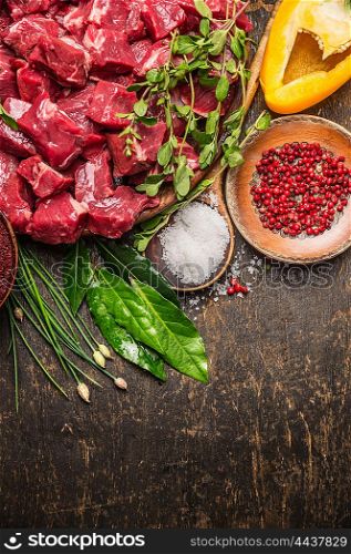 Chopped raw meat with vegetables, herb and spices for goulash on rustic wooden background, top view, place for text