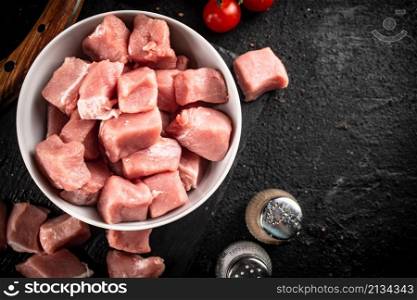 Chopped raw pork in a bowl. On a black background. High quality photo. Chopped raw pork in a bowl.