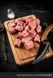 Chopped raw pork on a cutting board with knife, spices and rosemary. On a black background. High quality photo. Chopped raw pork on a cutting board with knife, spices and rosemary.