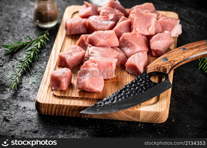 Chopped raw pork on a cutting board with knife, spices and rosemary. On a black background. High quality photo. Chopped raw pork on a cutting board with knife, spices and rosemary.