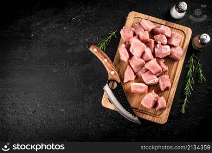 Chopped raw pork on a cutting board with knife, spices and rosemary. On a black background. High quality photo. Chopped raw pork on a cutting board with knife, spices and rosemary.