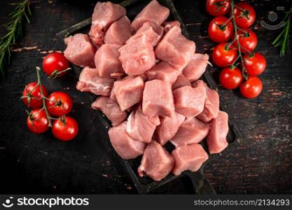 Chopped raw pork with fresh tomatoes and rosemary. Against a dark background. High quality photo. Chopped raw pork with fresh tomatoes and rosemary.
