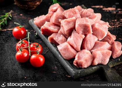 Chopped raw pork with fresh tomatoes and rosemary. Against a dark background. High quality photo. Chopped raw pork with fresh tomatoes and rosemary.