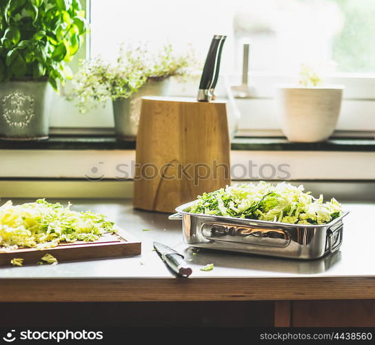 Chopped Savoy cabbage cooking preparation on kitchen table at window.