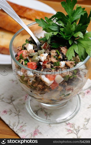 Chopped tuna with egg, cubes of tomatoes and olive slices , capers and parsley. Salad in a glass.