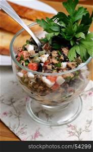 Chopped tuna with egg, cubes of tomatoes and olive slices , capers and parsley. Salad in a glass.