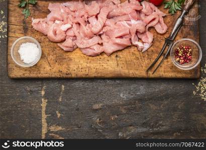 chopped turkey breast with salt and pepper and fork meat on a cutting board border ,place for text on wooden rustic background top view close up