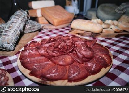 Chopping board of bresaola on a table of local products from the mountains of northern Italy