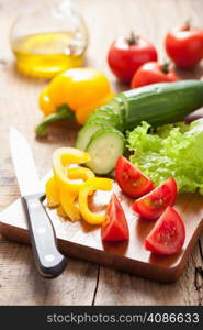 chopping fresh vegetables cucumber tomatoes pepper and salad leaves