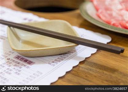 Chopsticks and serving dish on menu in Chinese restaurant