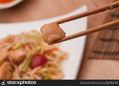 chopsticks with meat on a plate background with noodles. chopsticks with meat