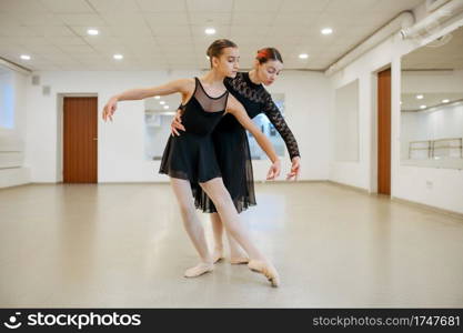 Choreographer works with young ballerina in class. Ballet school, female dancers on choreography lesson, girls practicing grace dance. Choreographer works with young ballerina in class