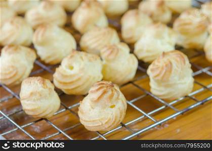 choux cream. fresh choux cream on a cooling grid over wooden table
