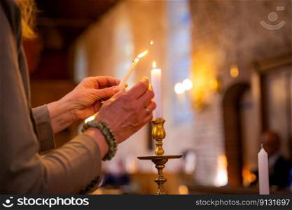 Christian and Catholic relics used during a worship service in a medieval Protestant church on a noble estate. Human hands with burning candles in church lighting holy candle