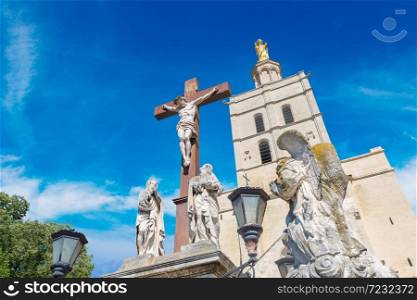 Christian cross in front of Cathedral and Papal palace in Avignon in a beautiful summer day, France