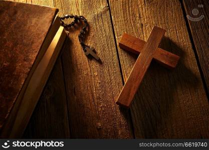 Christian cross on wood bible and rosary beads over wooden vintage background