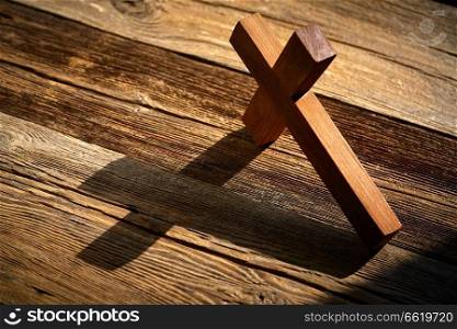 Christian cross on wood over wooden background vintage with shadows