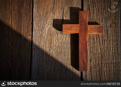 Christian cross on wood over wooden background vintage with shadows