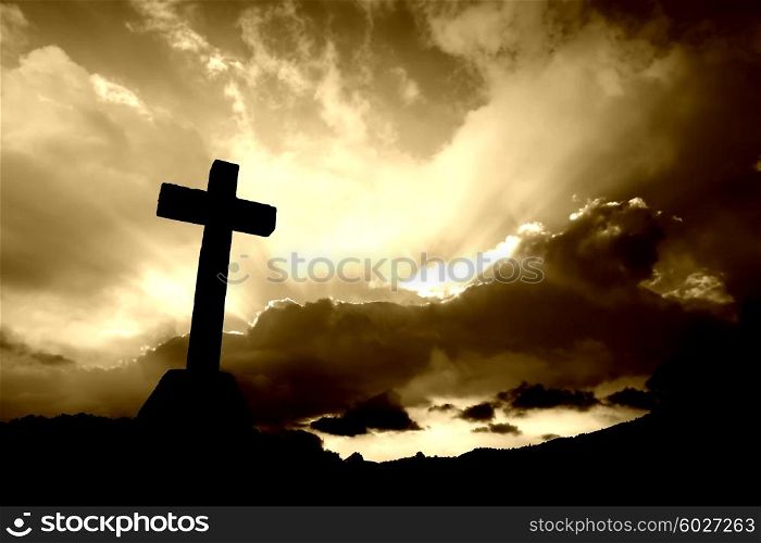 christian cross silhouette and the clouds in sepia tone