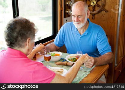 Christian senior couple in their motor home, saying grace over their meal.