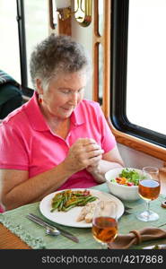 Christian senior woman saying grace over a healthy meal in her motor home.