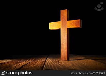 Christian wood cross on black and wooden background