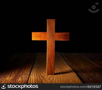 Christian wood cross on black and wooden background