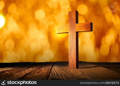 Christian wood cross on blur flare lights and wooden background