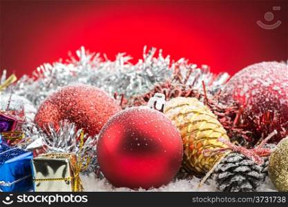 christmas accessories, gift boxes and spheres on snow on red background