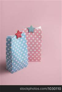 Christmas Advent calendar concept. Pink and blue gift bags with numbers on a pink background. His and her Xmas presents. Colorful gift bags.
