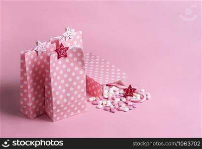 Christmas Advent calendar concept with gift bags in pink and white dots with numbers, marshmallows, and candy canes. Xmas tradition. Christmas frame.