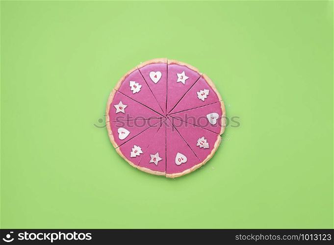 Christmas Advent context with a pink chocolate pie slices with numbers on it. Chocolate tart on green table. Numbered pie slices. Limited pie pieces.
