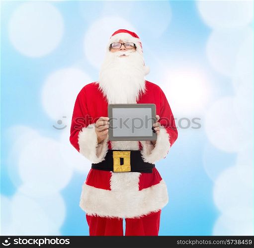 christmas, advertisement, technology, and people concept - man in costume of santa claus with tablet pc computer over blue lights background
