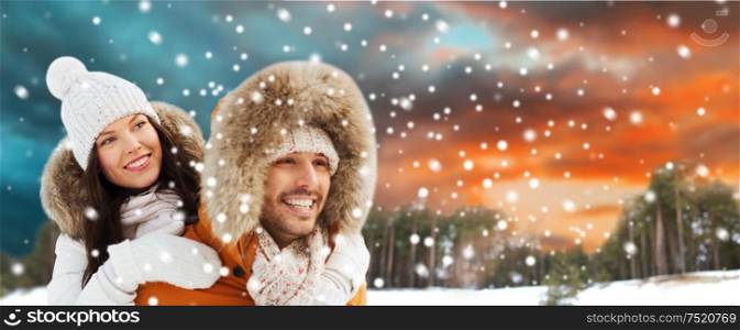 christmas and holidays concept - happy couple having fun over winter forest background. happy couple having fun over winter background