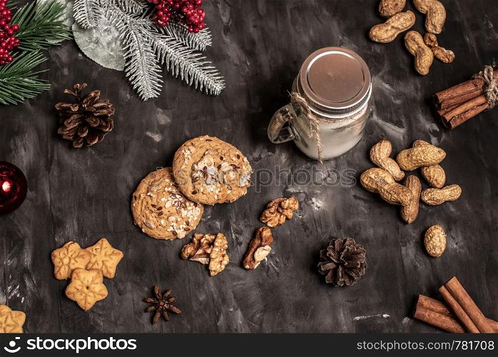 Christmas and new year celebration table decoration background with garland, cookies, pine cones, wallnuts and candle in cup. Christmas and new year table decoration background with garland, cookies, pine cones, wallnuts and candle in cup