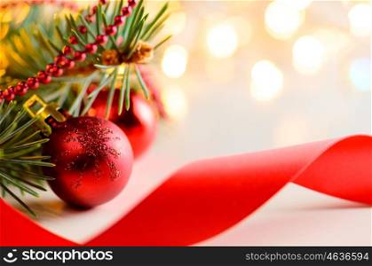 christmas and new year fir-tree with red glass balls, bow and festive garland lights blurred background