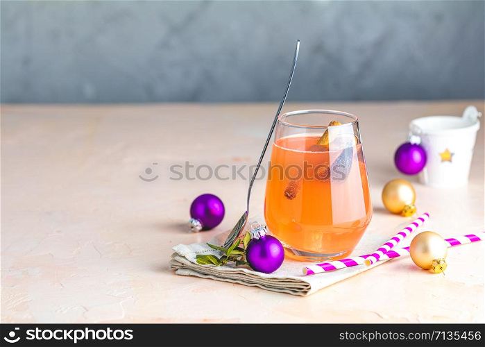 Christmas and New Year pink cocktail with fig and cinnamon in glass on pink concrete background, close up, surrounded holiday decor. Winter festive drinks and alcoholic cocktails or detox drink