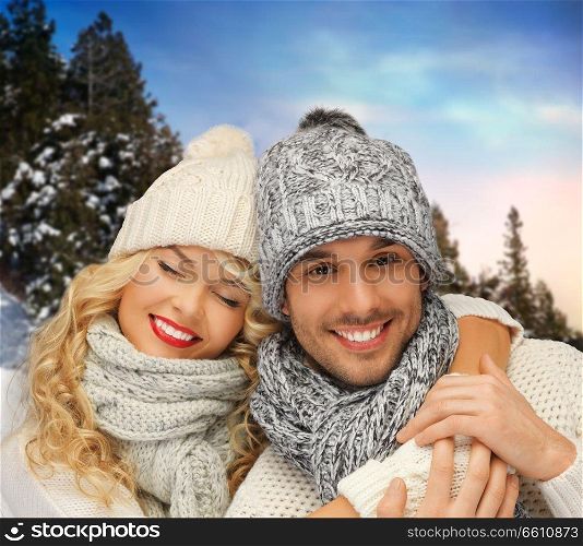 christmas and people concept - smiling couple in sweaters and hats over winter background. smiling couple in sweaters over winter background