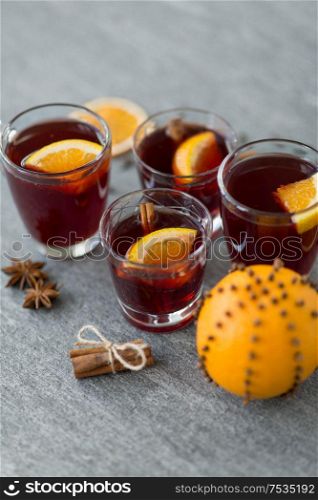 christmas and seasonal drinks concept - glasses of hot mulled wine with orange and cinnamon on grey background. glasses of mulled wine with orange and cinnamon