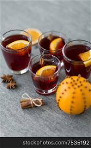 christmas and seasonal drinks concept - glasses of hot mulled wine with orange and cinnamon on grey background. glasses of mulled wine with orange and cinnamon
